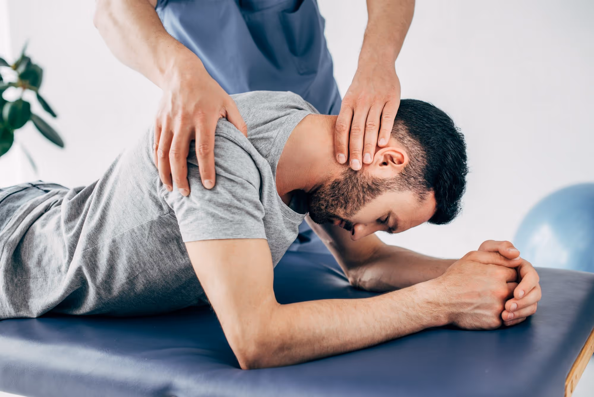 foto di uomo con t-shirt grigia e taglio di capelli corti sul quale viene applicata una presa da parte di un professionista osteopata